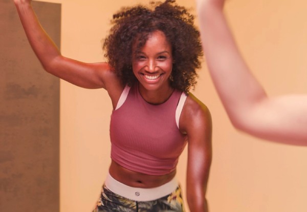 Bild: Eine lächelnde Frau führt im Kursraum eine dynamische Übung aus. Daneben steht der Hinweis, dass man bei FitX online Mitglied werden kann.